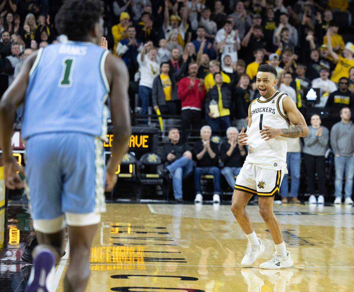 Wichita State’s Xavier Bell looks back at Tulane’s Kaleb Banks after hitting a three-pointer during the second half of their game on Sunday at Koch Arena.