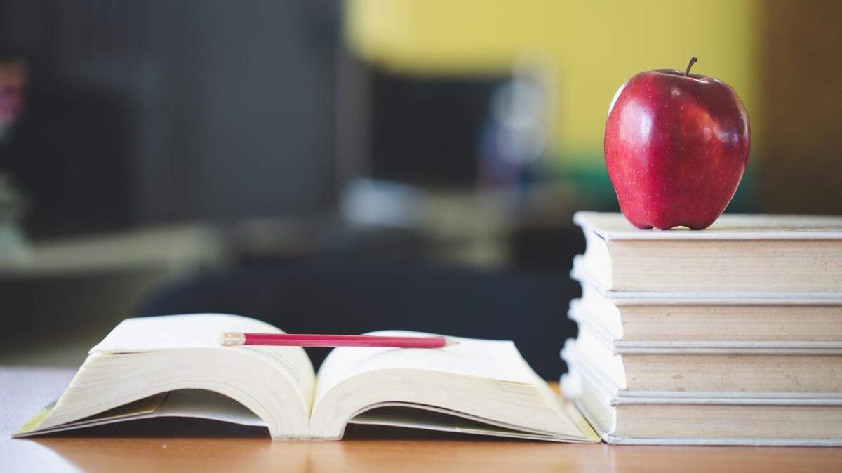 School teacher’s desk with stack of books and an apple.