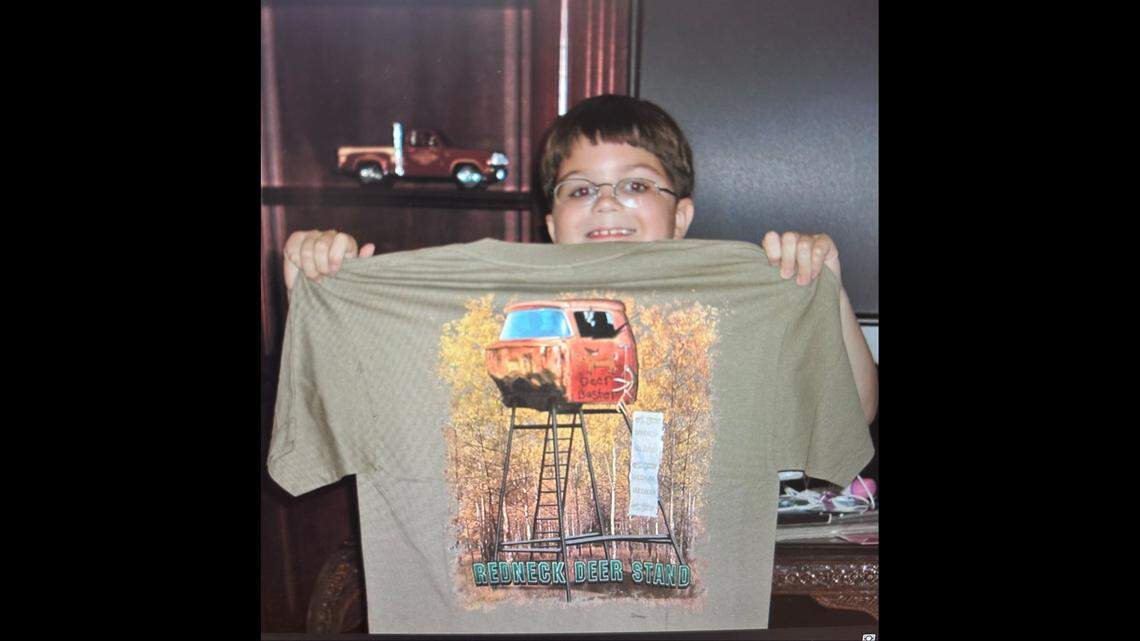 A photo of Jesse Pitcher when he was young holding up a hunting T-shirt.