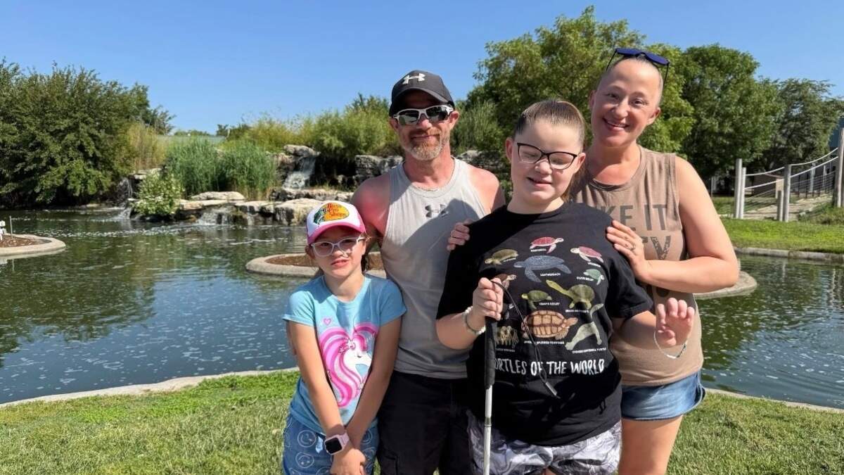 Dallas Fronken stands with her mom and dad, Chad and Sarah Fronken, and little sister, Khloe Fronken, in front of a small man-made pond. Dallas, standing at the front, is a visually impaired student attending the 2026 Braille Challenge finals.