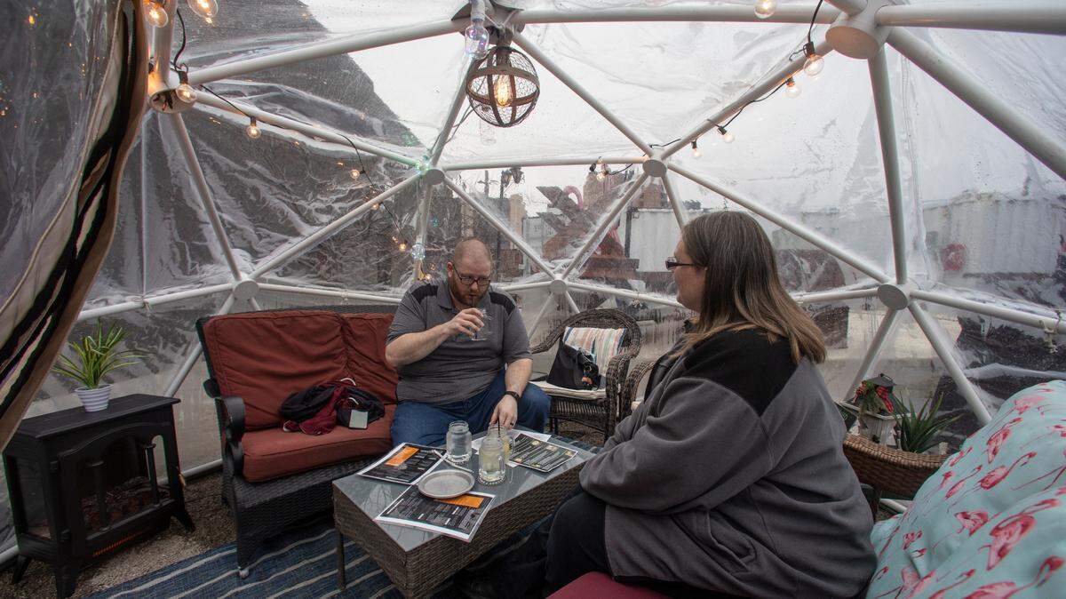 Kris, left, and Victoria Shoemaker enjoy a drink inside one of the igloos that Nortons Brewing Co. purchased to add outdoor seating while indoor seating is at 50% capacity due to the coronavirus. Downtown business owners say the pandemic is causing them particular problems due to the lack of people in the area.