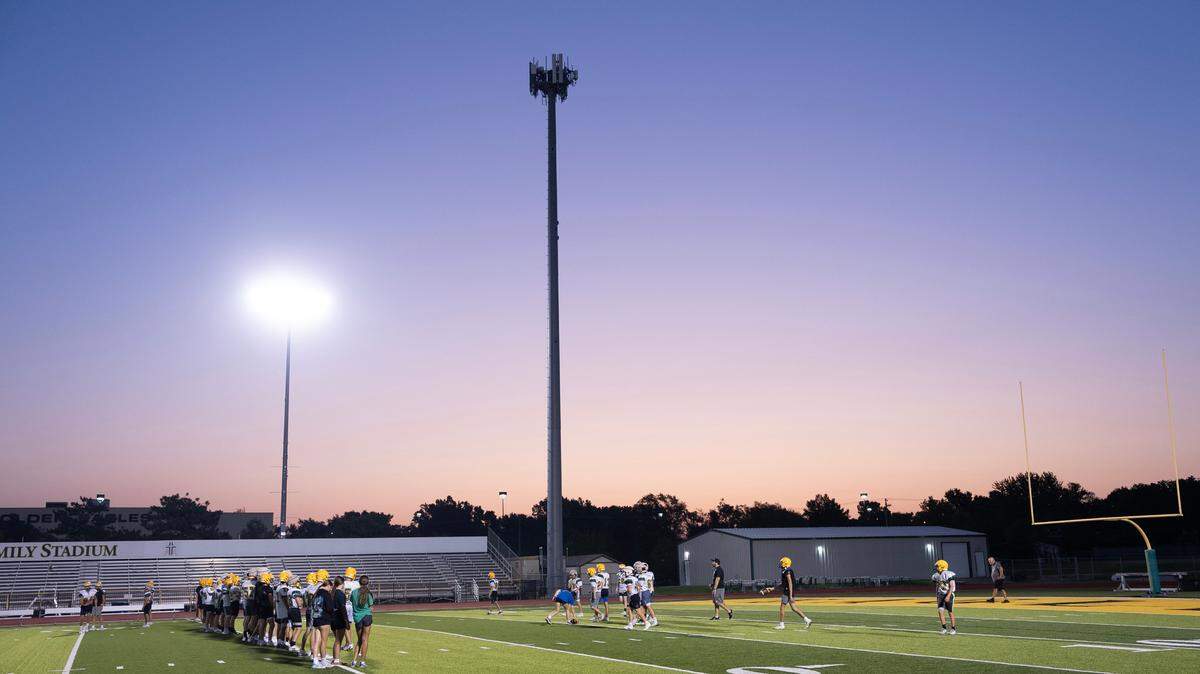 The football team at Bishop Carroll Catholic High School practices at sunrise on Tuesday. The team is starting practice at 5:30 a.m. this week to avoid the extremely high temperatures.