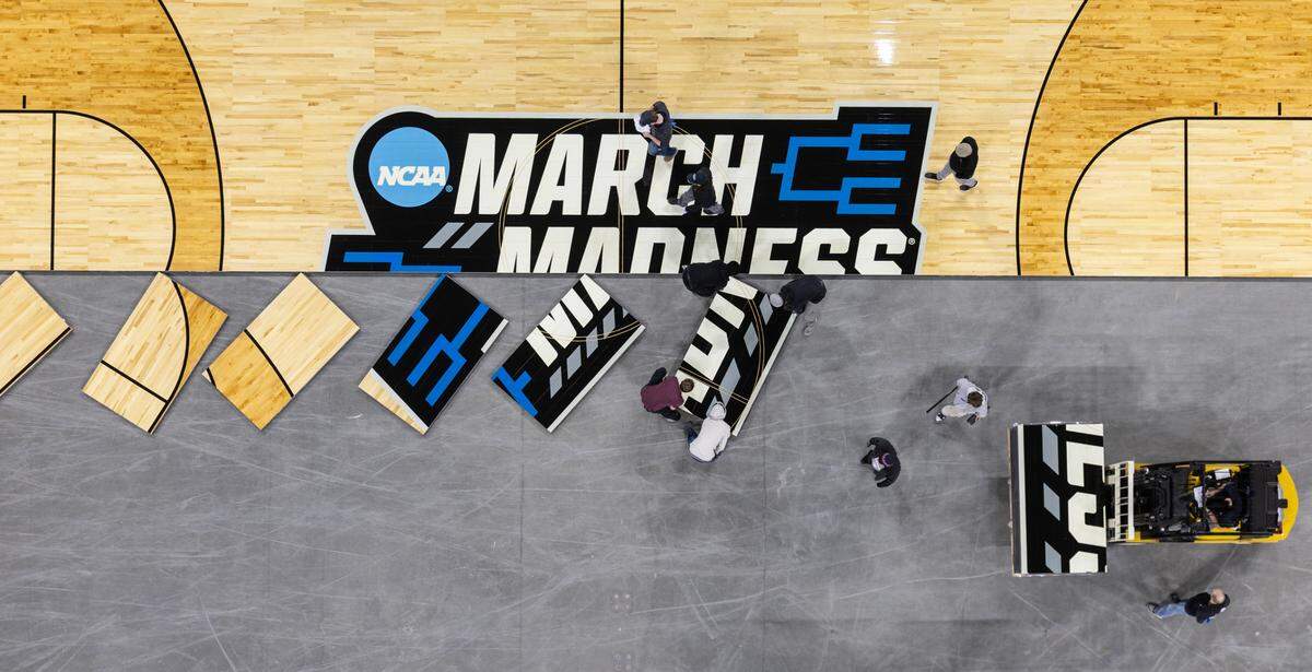 Workers install the court for the upcoming NCAA Tournament at Intrust Bank Arena on Sunday morning. 