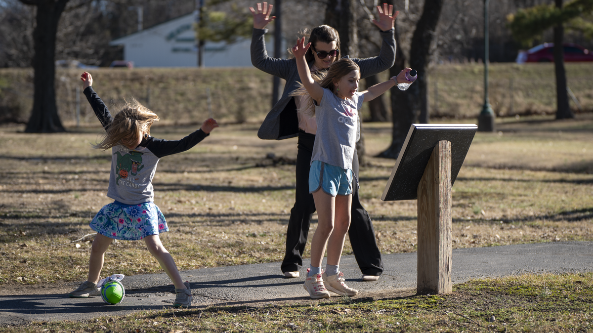 Children interact with one of Kelley Donner’s permanent book displays on an outdoor path.