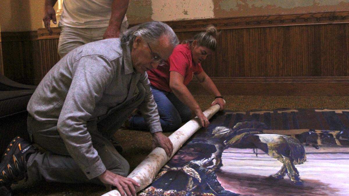 Wichita artist Steve Murillo and city council member Maggie Ballard, right, roll up the mural in the Eaton Place building. It had been scheduled to be demolished Monday.