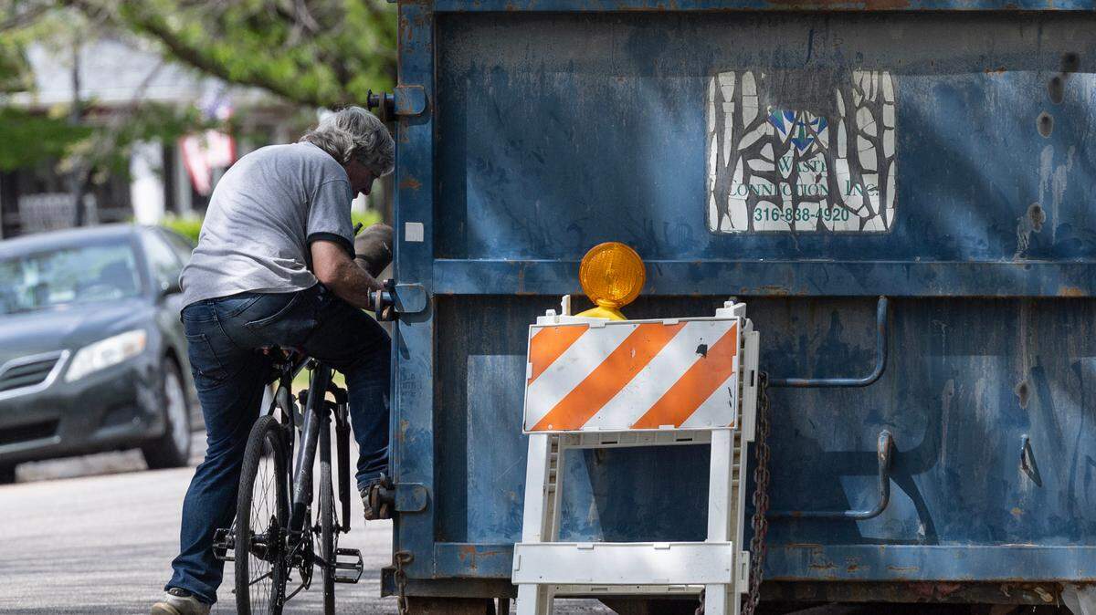 A man looks for scrap material in a dumpster at a construction site in Delano in this April 23, 2025, photo.