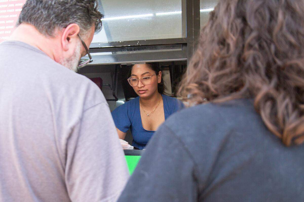 Nikki Shrestha serves customers at The Momo Stop. Shrestha is married to Unnat Ghimire, who owns the local Nepali food truck.