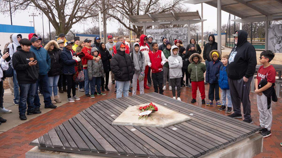 League 42 director Bob Lutz, far right, addressed the crowd of 80 people gathered at the Jackie Robinson pavilion at McAdams Park Saturday morning. Roses were placed along with a note that read “We Miss You” where a statue of Jackie Robinson once stood. Thieves cut down and stole the bronze statue of Robinson valued at $75,000 from the League 42 facility at McAdams Park early Thursday morning.