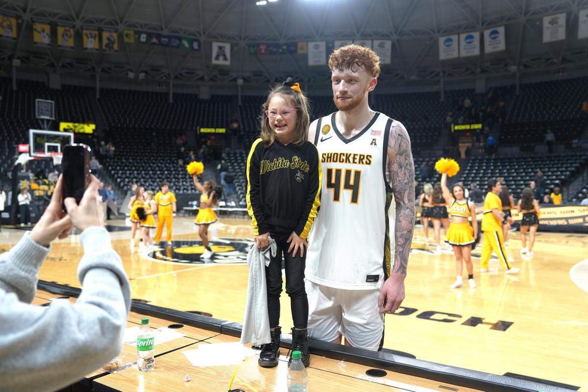 Celine Cline, 5, takes a picture with her favorite Wichita State basketball player Will Berg after WSU’s game against Charlotte.
