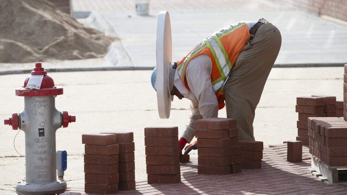 Rojelio Rebeles, with Heartstone, uses a piece of styrofoam around his hardhat to provide shade from the sun while laying bricks on Second St. in Old Town in 2019.