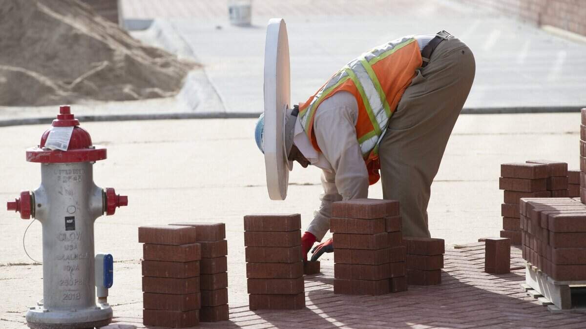 Rojelio Rebeles, with Heartstone, uses a piece of styrofoam around his hardhat to provide shade from the sun while laying bricks on Second St. in Old Town in 2019.