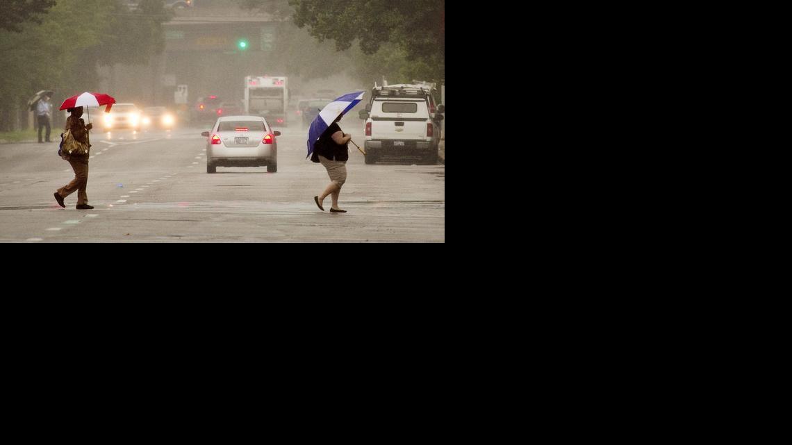 Pedestrians make their way across Broadway in downtown Wichita during a Monday morning shower. Rain, some possibly heavy, is expected through Tuesday. (June 9, 2014)

