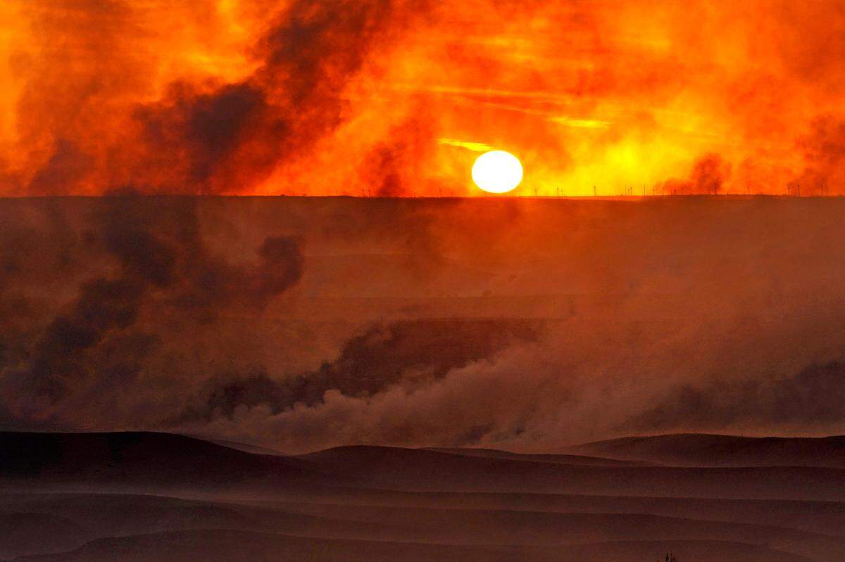 The setting sun is shrouded in smoke from a fire that burned and stretched across Ellis, Russell, Osborne and Rooks counties Thursday, Dec. 16, 2021, near Natoma, Kan. Firefighters and emergency responders are battling fires spreading across parts of central and western Kansas after a powerful storm blew through the state. (AP Photo/Charlie Riedel)