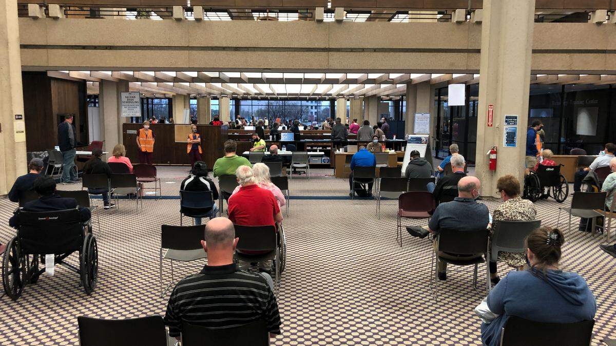 People wait inside the former downtown public library after receiving a COVID-19 vaccination. There is a 15-minute suggested wait time after the injection. (April 6, 2021)