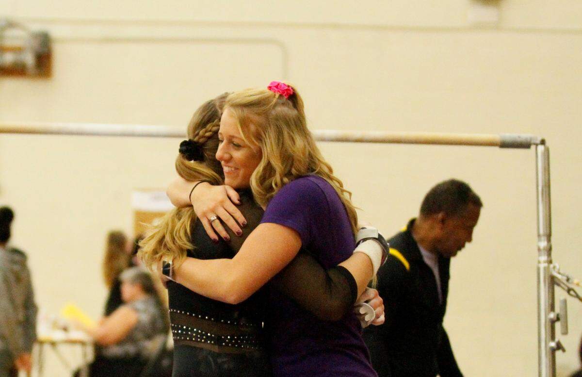 Newton assistant gymnastics coach Carlye Anderson huge a Railer gymnast after her uneven bars routine during Newton’s home meet against Emporia on Monday. (Oct. 8, 2018)
