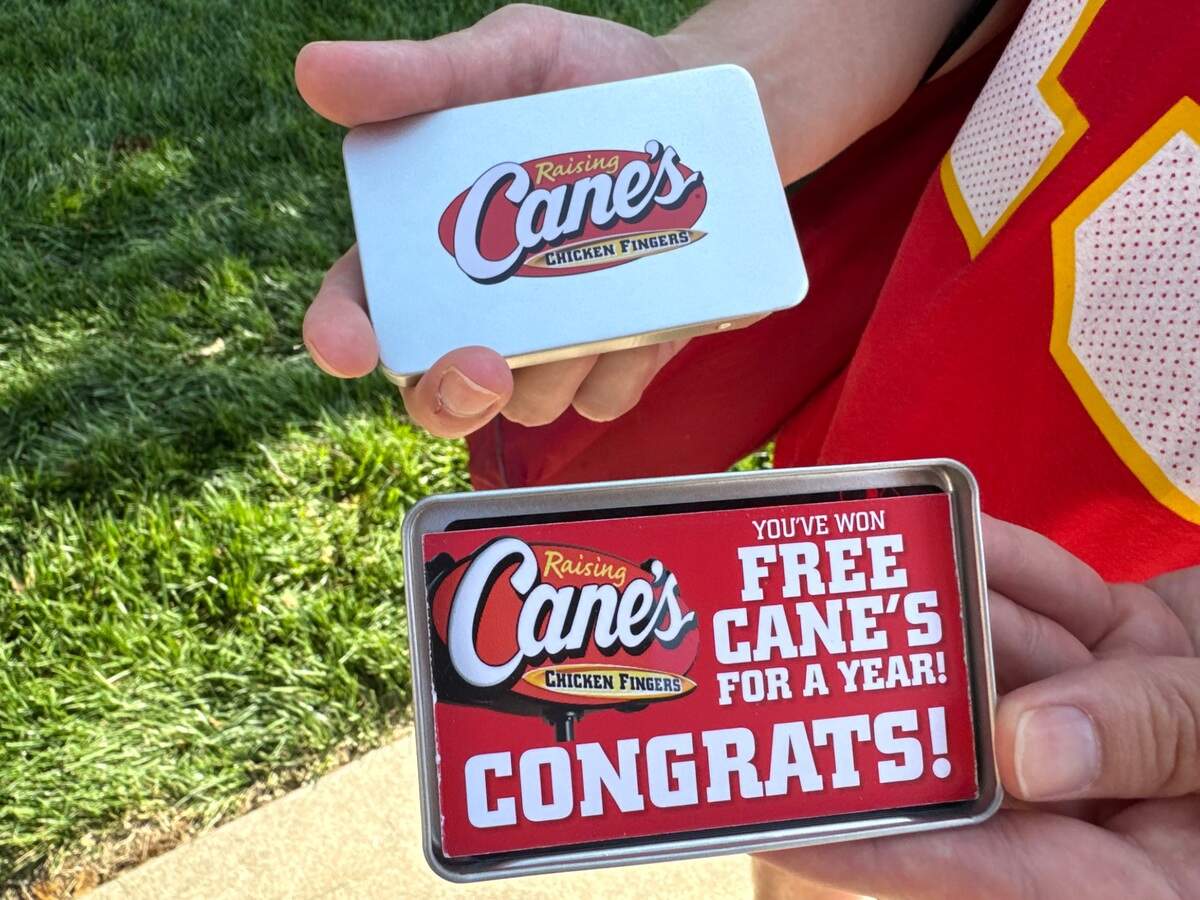 One of the 20 winners of free chicken for a year displays his prize at Tuesday morning’s Raising Cane’s opening in Wichita.