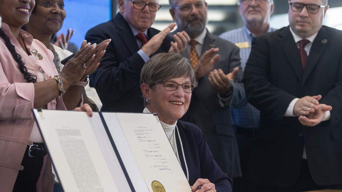 Gov. Laura Kelly holds up Senate Bill 127 after she ceremoniously signed it into law at the Advanced Learning Library on Friday afternoon. Under the new law, people who are struggling to pay fines and fees can ask a judge for a reduction or waiver based on hardships. The bill is intended to give help to the thousands of Kansas with suspended drivers licenses.