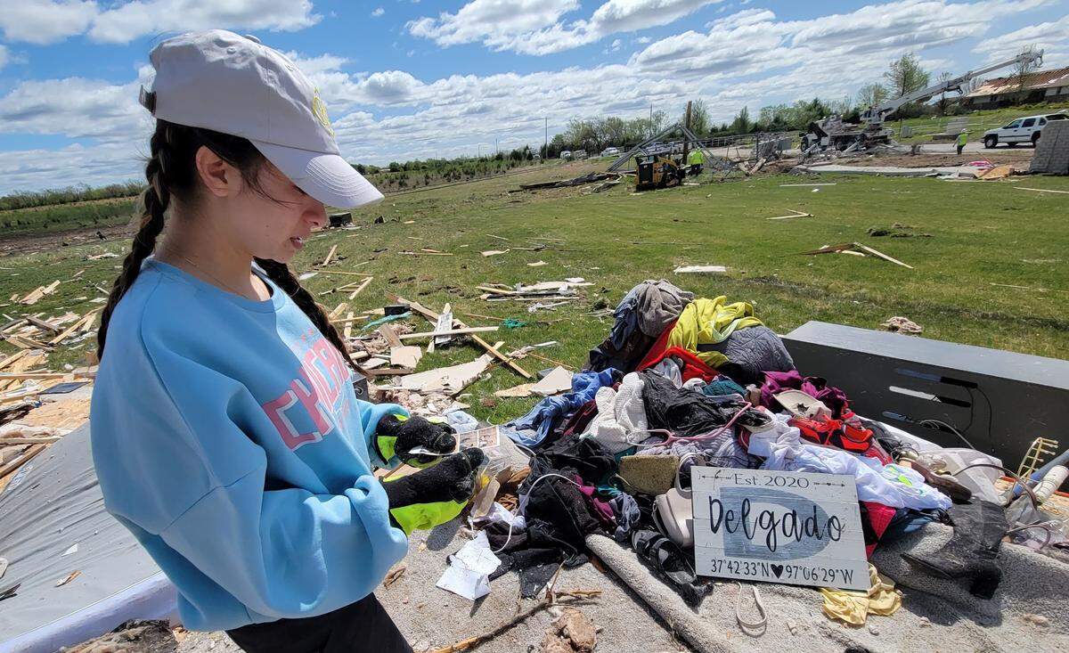 On Saturday, Flor Delgado finds a photo of she and her husband while sifting through their belongings following the Andover tornado the night before. The pile of stuff she wants to keep lies in what used to be the corner of their home.