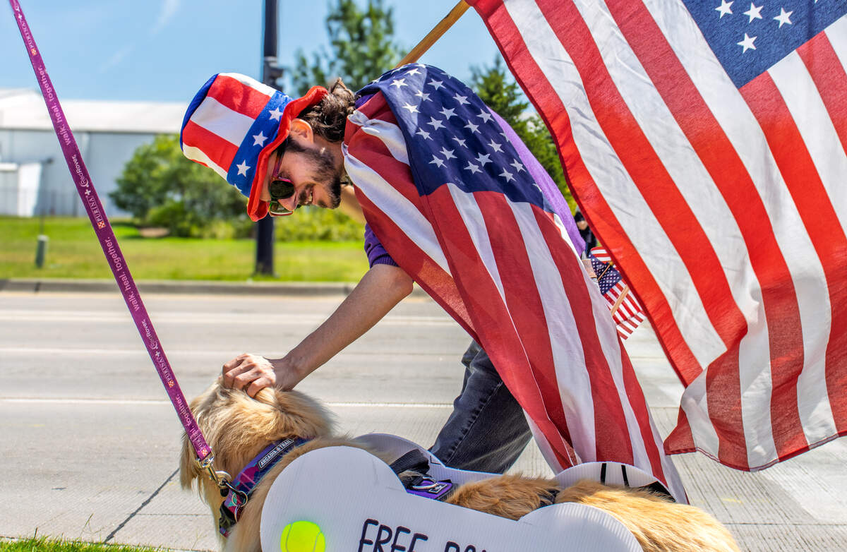 Mark Barlow, a member of Leading Kansas and an avid protester, pets Odin "Odie" the golden retriever while protesting Sen. Roger Marshall’s support of Trump policies on Aug. 26. Marshall spoke at the Wichita Regional Chamber of Commerce's federal issue forum.