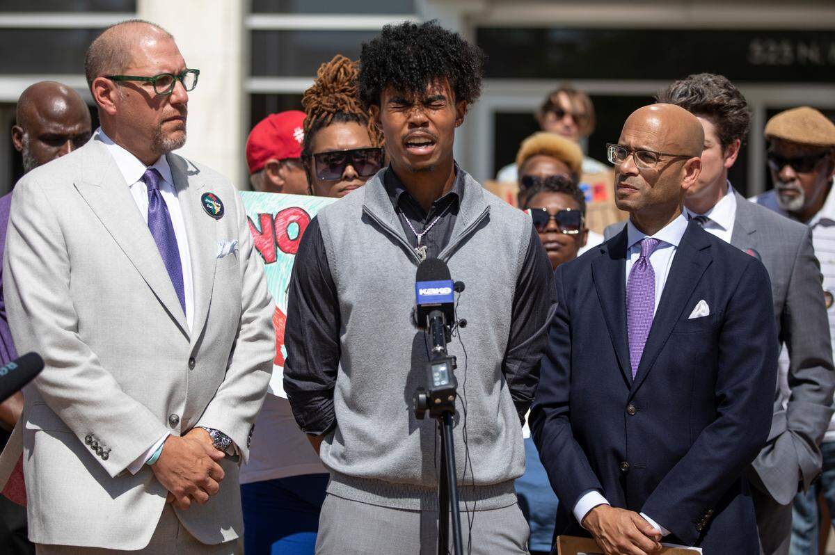 Marquan Teetz, middle, the brother of Cedric Lofton, becomes emotional while speaking outside the Sedgwick County Courthouse on Monday. Teetz is flanked by his attorneys, Andrew Stroth, right, and Steven Hart, left. Teetz, acting as representative of Lofton’s estate, has sued Sedgwick County, five detention center employees, the city of Wichita, and the unidentified police officers. Cedric Lofton died in September 2021 after officers at a juvenile intake facility forcibly held him down for around 40 minutes.