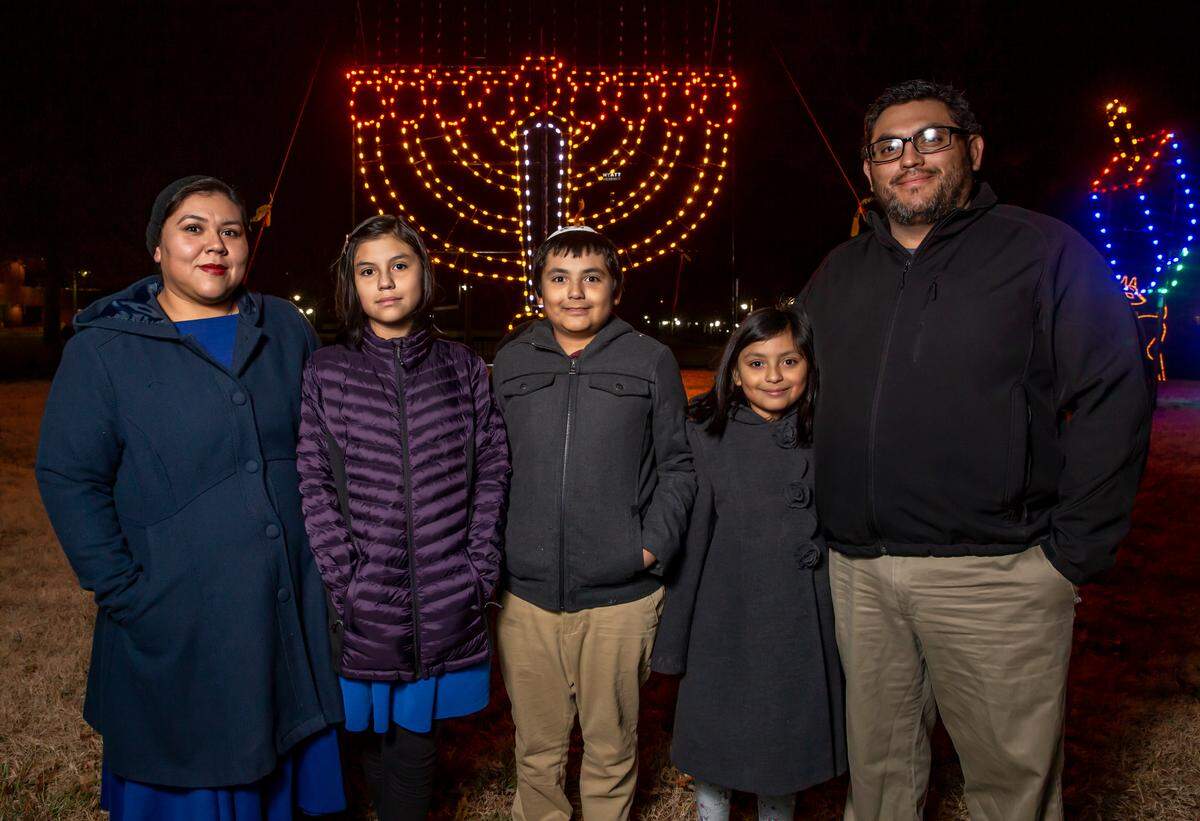David and Maggie Pichinte and their children Bella, 11, Elijah, 9, and Sara, 8, left to right, were instrumental in getting some Jewish decorations put up near Century II. They stand in front of a menorah Thursday night.