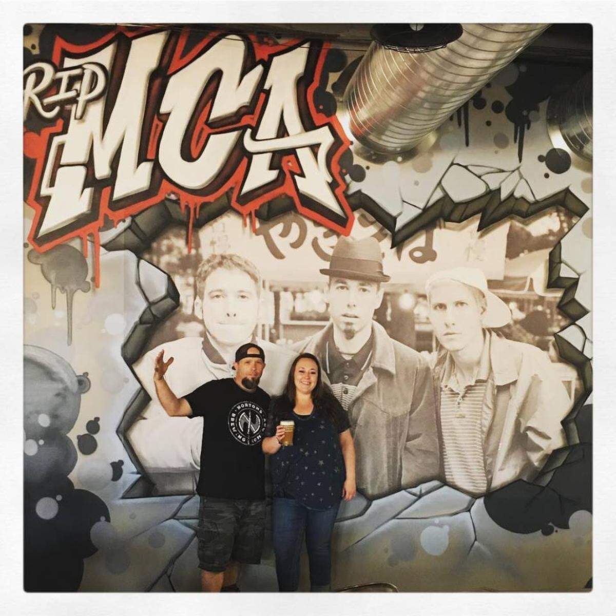 Nortons Brewing Company owners Dan and Becky Norton pose in front of their south wall, which features a mural of the Beastie Boys.