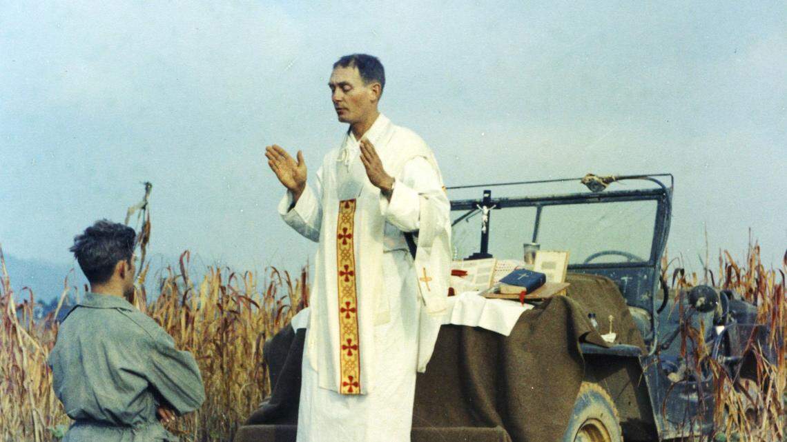 The most iconic photo of Father Kapaun. It was taken Oct. 7, 1950, less__than a month before he was taken prisoner. In the photo, Kapaun__celebrates Mass using the hood of his jeep as an altar. Kneeling is__Kapaun’s assistant, Patrick J. Schuler, who was with him the night he__was captured.__Courtesy of Raymond Skeehan