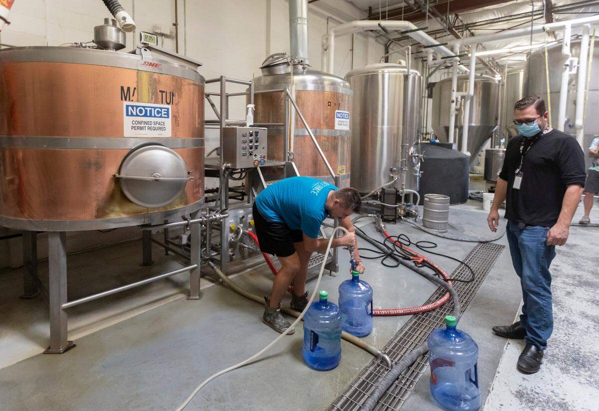Cody Sherwood, left, a brewer for the Wichita Brewing Company, fills water bottles for Chris Hart on Friday at the company’s brewing facility in Wichita. A water main rupture in Wichita has forced all the residents of Kansas’ largest city into a mandatory water boil advisory until further notice. Wichita Brewing company posted to their Facebook page Friday morning page that they had 900 gallons of treated water they were willing to give away for free for anyone in need. 