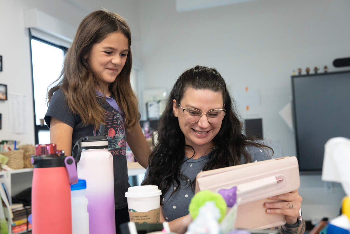 Creative Minds student Ilana Villanueva, left, shows Olivia Sumner, a picture of what Chat GPT thinks her dog looks like. Sumner teaches 16 students in one classroom, kindergarten through sixth grade.