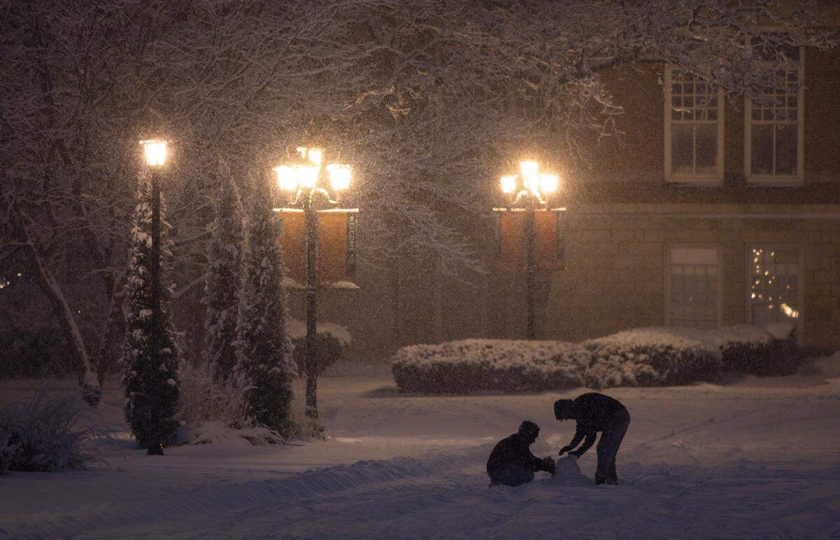 Two students work on a snowman at Friends University on Thursday night.