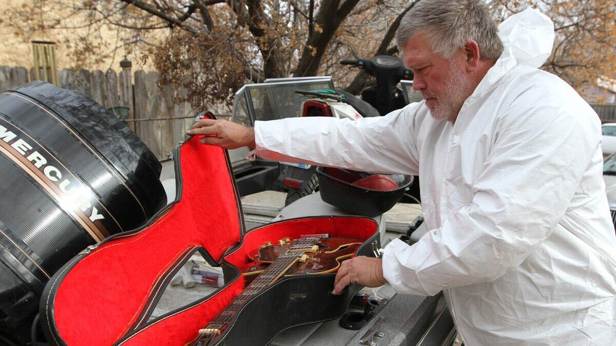 Michael Epperson Jr. looks at a guitar that belonged to his father, Michael Epperson Sr., who was killed in January in his west Wichita home. The home caught fire and many items burned. The guitar has fire damage, but Epperson Jr. plans to get it restored to remember his father by.