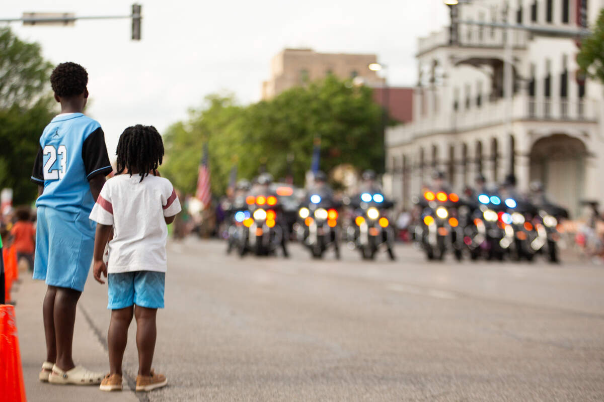 Before the start of the Star Lumber Sundown Parade, children stand and watch as the Wichita Police Department motorcycle unit get in position to lead the parade on Friday.