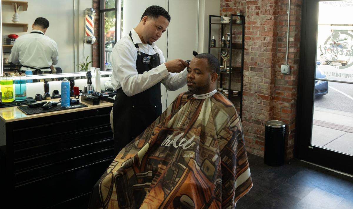 Barber Javier Garcia works on his longtime client Patrick Penn at his shop near the corner of Douglas and St. Francis. His customers will soon have to pay for parking,