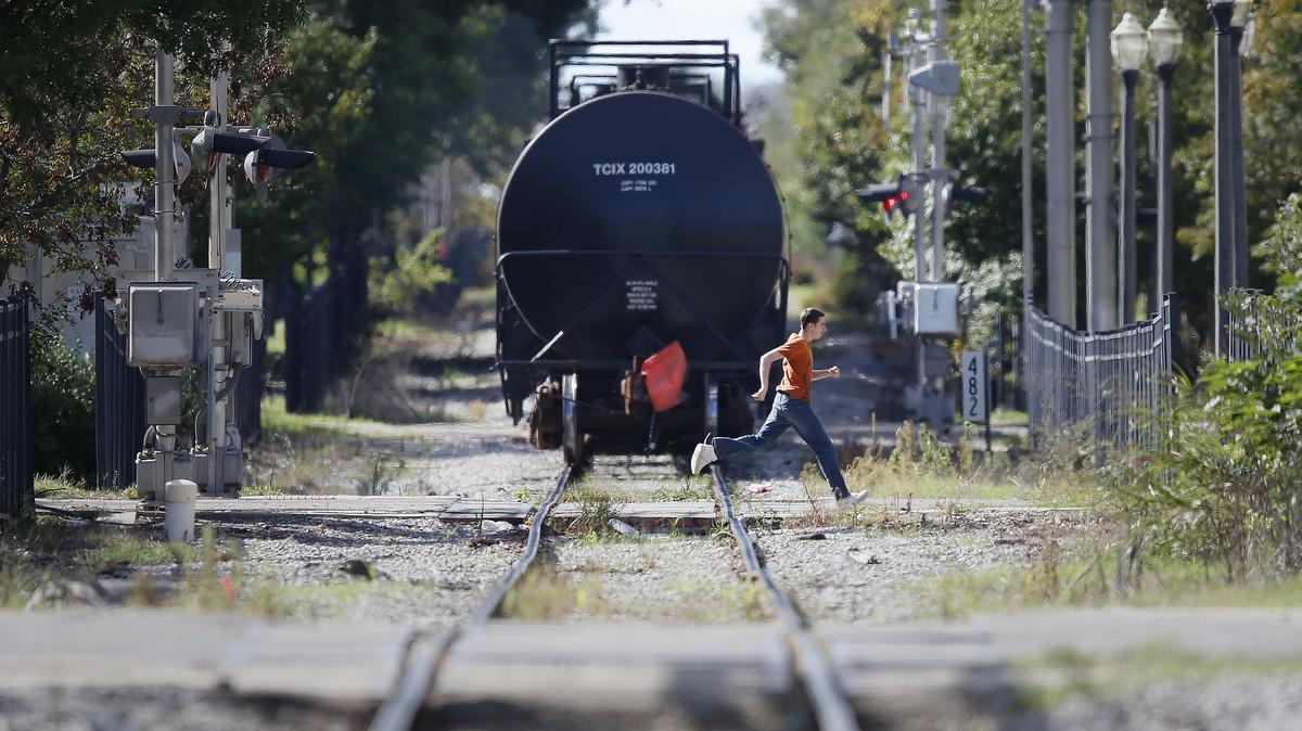 A student from Hamilton Middle School runs north on Market Street Wednesday afternoon just after a train passed by. Trains sometimes block students’ path to and from school. A teacher saw students crawling under a stopped train this week to get home, sparking warnings from the school. (October 10, 2018)
