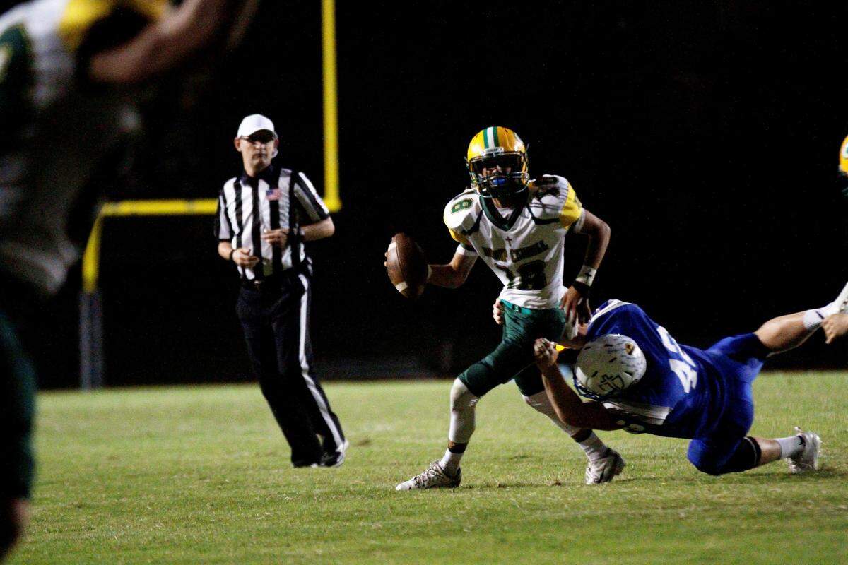 Aiden Niedens, a Bishop Carroll sophomore quarterback, holds off a Kapaun defender while looking downfield during the Golden Eagles’ 28-14 win at Kapaun on Friday. (Oct. 5, 2018)
