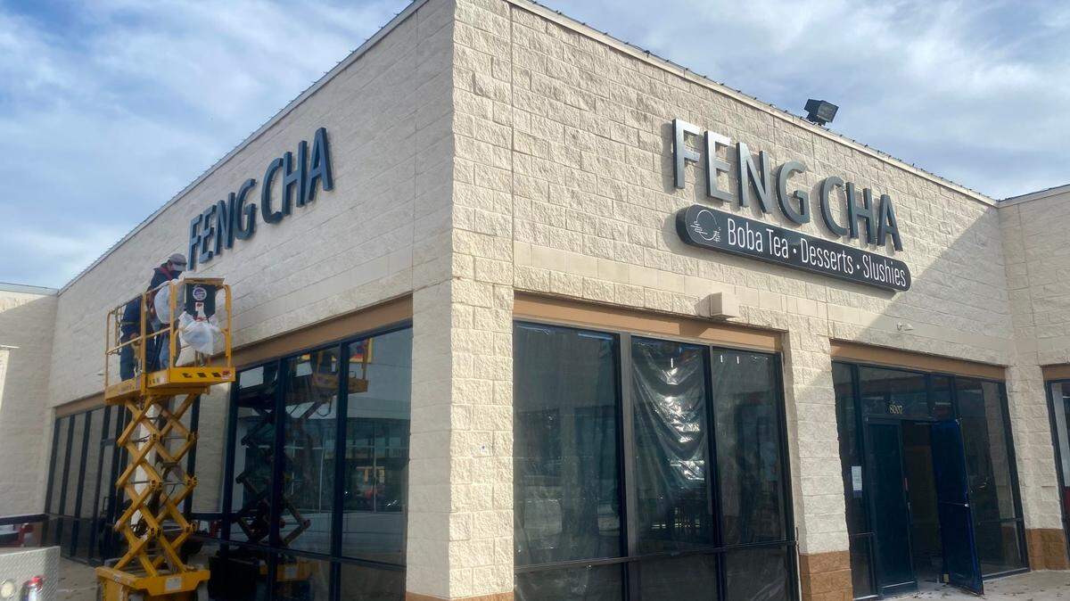 Workers hang the sign on Tuesday for the new Feng Cha at Eastgate Plaza.