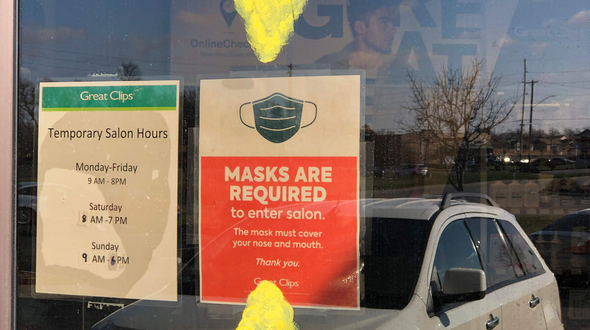 Great Clips at 13303 W. Maple St. displays a sign on its front door with arrows pointing to it that masks are required. (March 18, 2021)