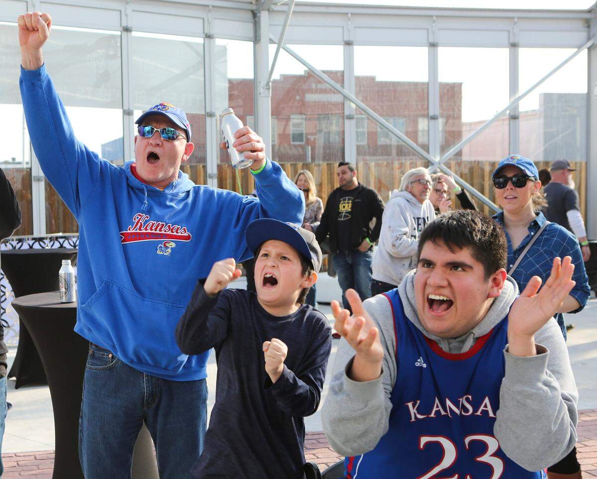 In 2018, University of Kansas basketball fans (left to right) Clay Williams, Manny Rodriguez and Jose Rodriguez celebrated at the Brick & Mortar Event Venue after it was announced that KU would play as the number-one seed in the first and second rounds of the NCAA Tournament at Intrust Bank Arena.