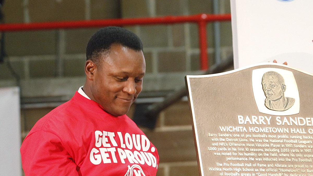 Hall of Famer Barry Sanders, left, and Wichita Vice Mayor  Lavonta Williams unveil the plaque that was given to him by the Pro Football Hall of Fame and Allstate and that he is donating to North High during a pep rally Thursday. (Oct 27, 2011)