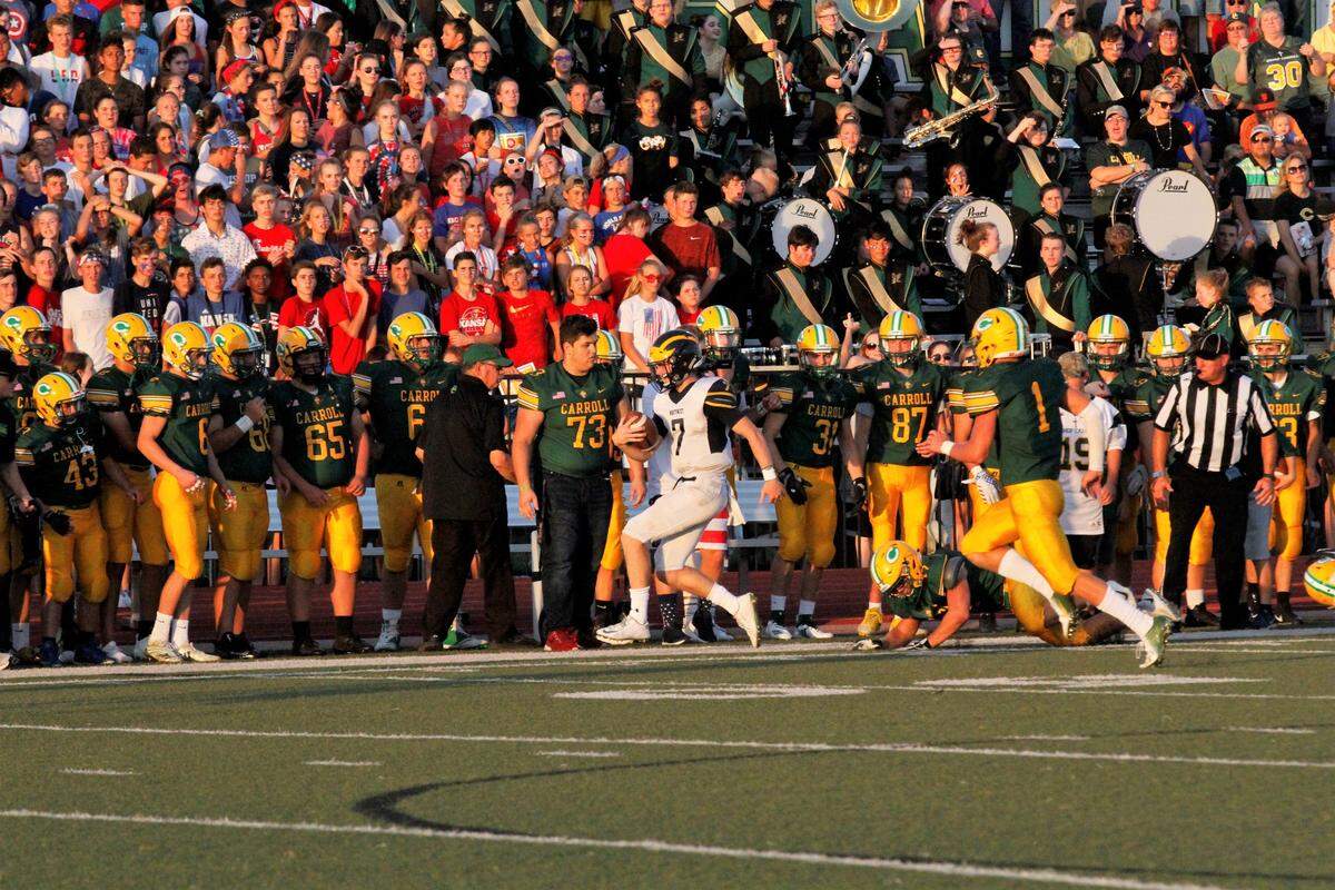 Wichita Northwest junior quarterback Reagan Jones runs into the Bishop Carroll sideline as thousands of fans look on during the Grizzlies’ 23-22 road victory Friday night. (Aug. 31, 2018)