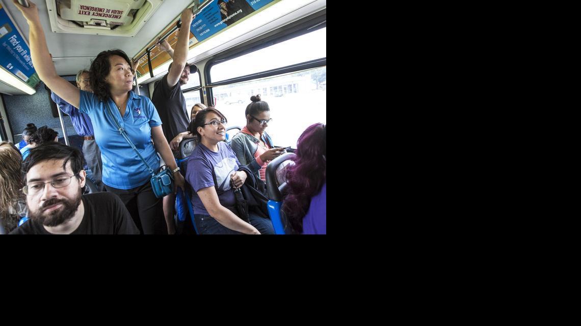 Stepstone program coordinator Dung Kimble, standing, and advocate Lorenza Rivas, right, ride a public bus as a “walk in her shoes” for the women and families they serve, who are victims of domestic violence. (July 17, 2014)