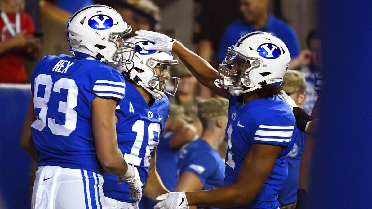 Brigham Young wide receiver Gunner Romney, center, celebrates a touchdown with teammates Isaac Rex, left, and Keanu Hill, right, during the second half of an NCAA college football game against Utah Saturday, Sept. 11, 2021, in Provo, Utah. (AP Photo/Alex Goodlett)