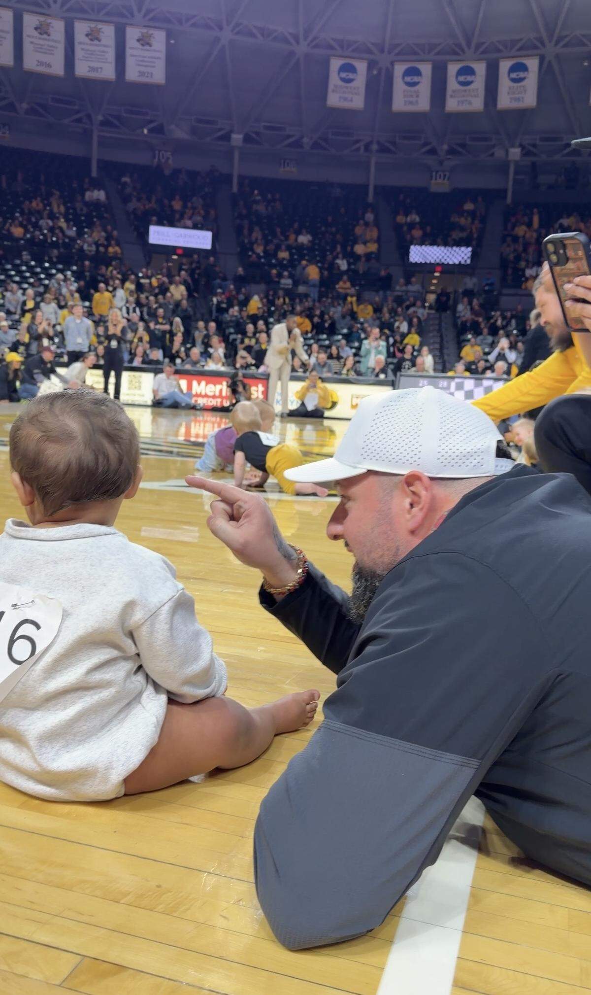 Matthew Medrano, right, gives baby Moses Hurst instructions during a Wichita State Shockers’ baby race last week.
