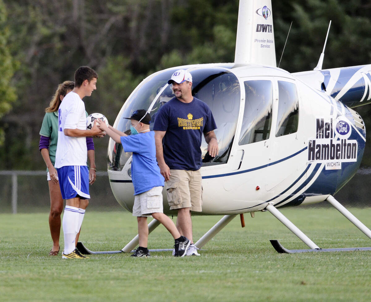Cole Clifton hands his brother Austin Clifton (12) of Northwest the ball before the game starts against Kapaun. Cole came into the field by the Mel Hambelton Hellicopter at Northwest on Sept 20th, 2011. PHOTO BY MARC BROWNING