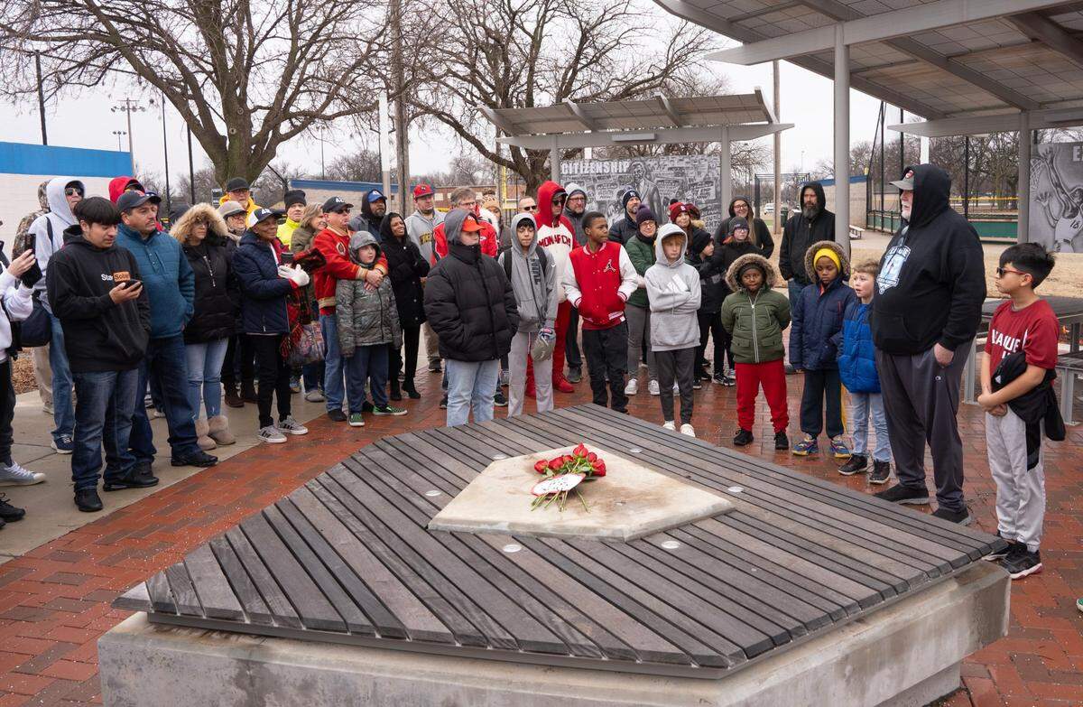 League 42 founder Bob Lutz, far right, addressed a crowd of about 80 people gathered at the Jackie Robinson pavilion at McAdams Park in January. Roses were placed along with a note that read, “We Miss You,” where a statue of Robinson previously stood. Thieves cut down and stole the bronze statue of Robinson, for whom the league is named, earlier that week.