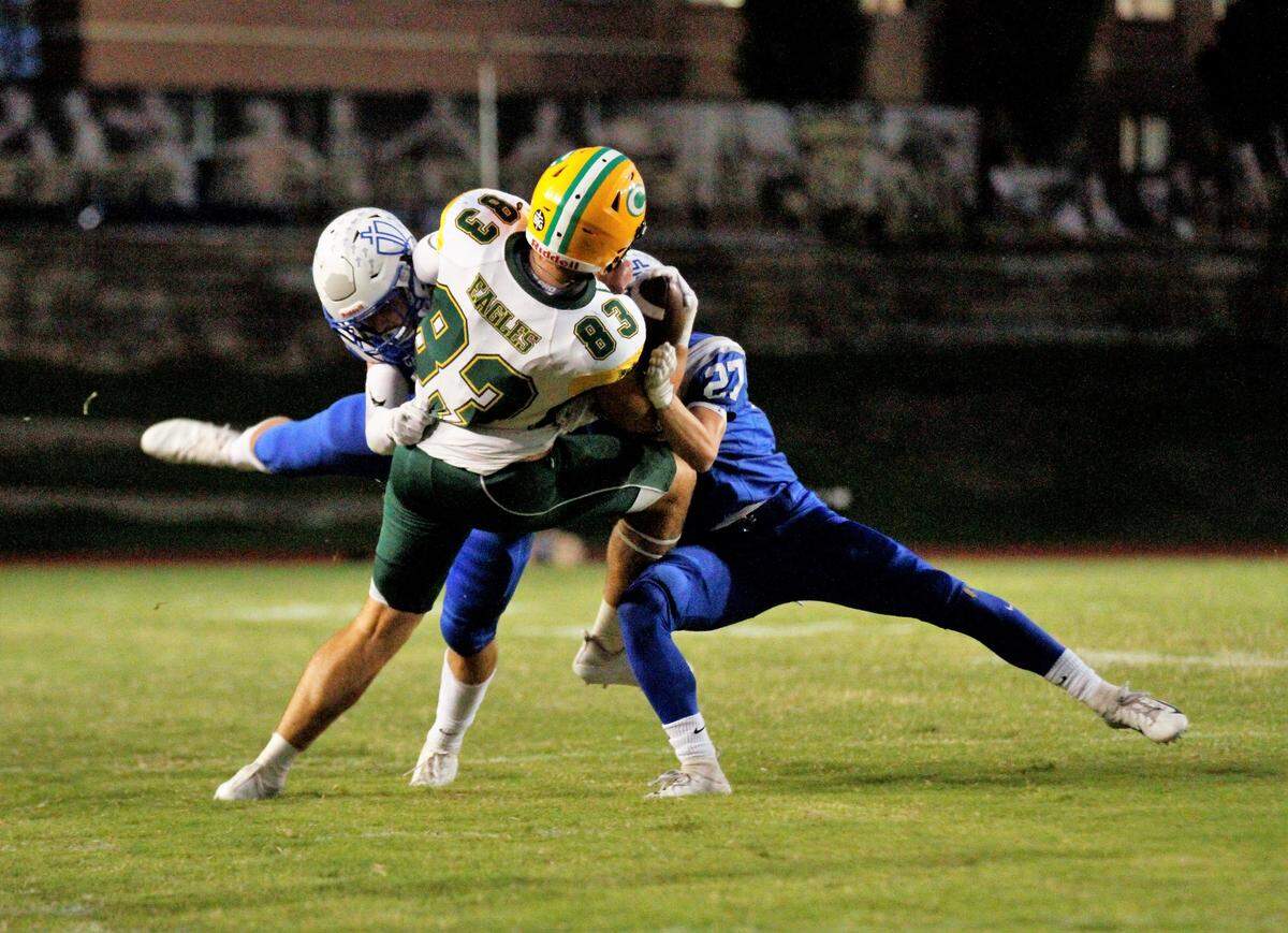Kapaun’s Scott Valentas (left) and Parker Manning (27) take down Bishop Carroll tight end Clay Cundiff during the Golden Eagles’ 28-14 win at Kapaun on Friday. (Oct. 5, 2018)