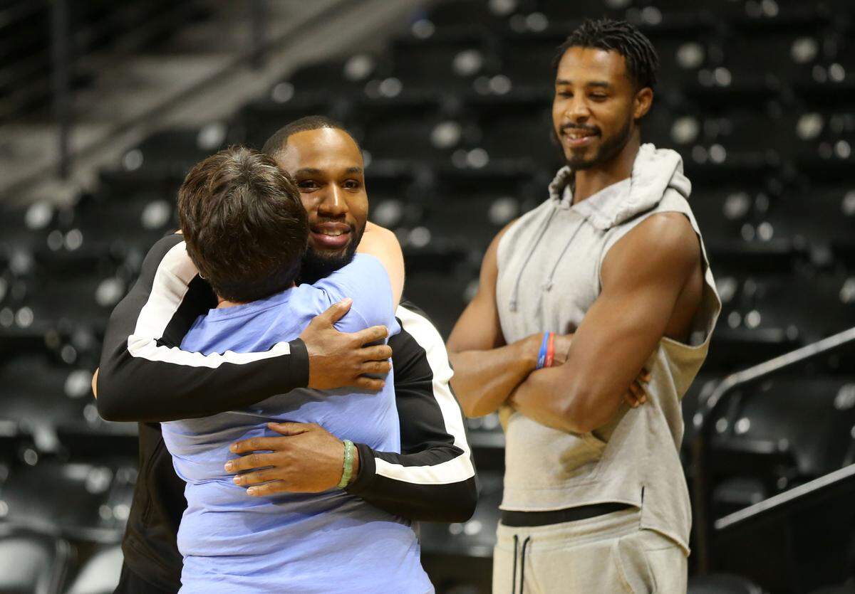 Tekele Cotton hugs hugs Jennifer Torline, Director of Athletic Academic Services, during the AfterShocks practice on Wednesday. Looking on is Toure’ Murry.(July 24, 2019)