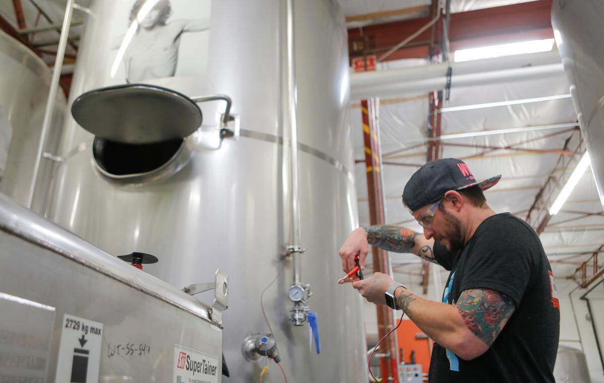Wichita Brewing Company co-owner Jeremy Horn wires up an electrical ground wire while the they prepared to make nearly 800 gallons of hand sanitizer in one of their brewing tanks on Tuesday.