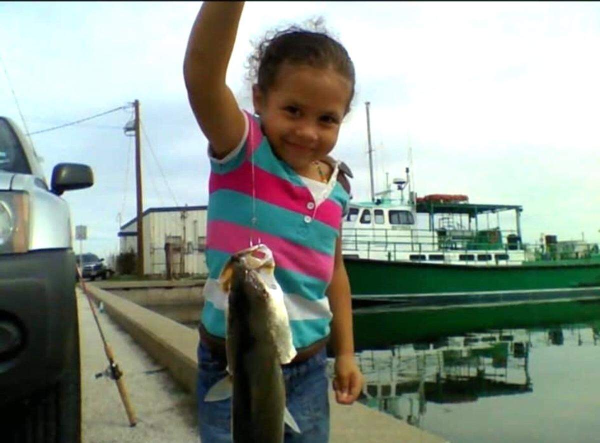 A childhood photo of Naomi Oglesby catching a fish.