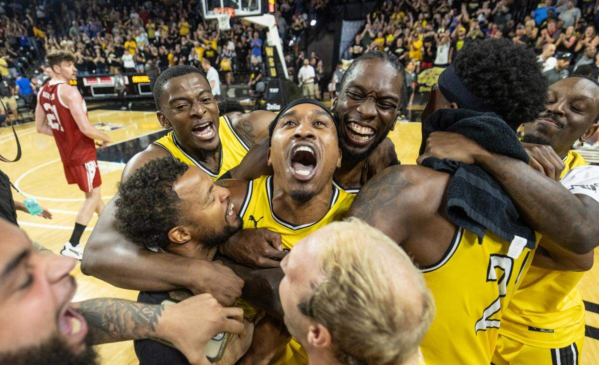 Tyrus McGee is mobbed by his AfterShocks teammates after his three pointer won the game against Team Arkansas on Sunday at The Basketball Tournament at Koch Arena. 